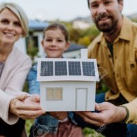 193026675-familia-feliz-sosteniendo-modelo-de-papel-de-casa-con-paneles-solares-energia-alternativa-ahorro