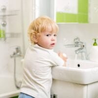 kid washing hands with soap in bathroom