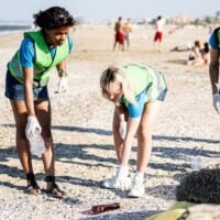 diversas-personas-limpiando-playa-voluntarios-recogiendo-desechos-costa-personas-turistas-playa-fondo_164678-1183
