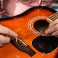 manos-cambiando-cuerdas-en-guitarra-acustica