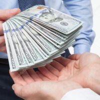 manos-intercambiando-dinero-y-documentos-financieros