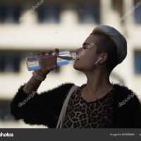 mujer-bebiendo-agua-en-botella-de-cristal
