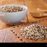 un-monton-de-materias-quinoa-y-amaranto-en-una-placa-de-madera-con-un-tazon-de-cereales-cocidos-en-el-fondo-ctgr62