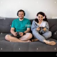 una-pareja-jugando-a-videojuegos-juntos-sentados-en-el-sofa-cama-2g3ycxc